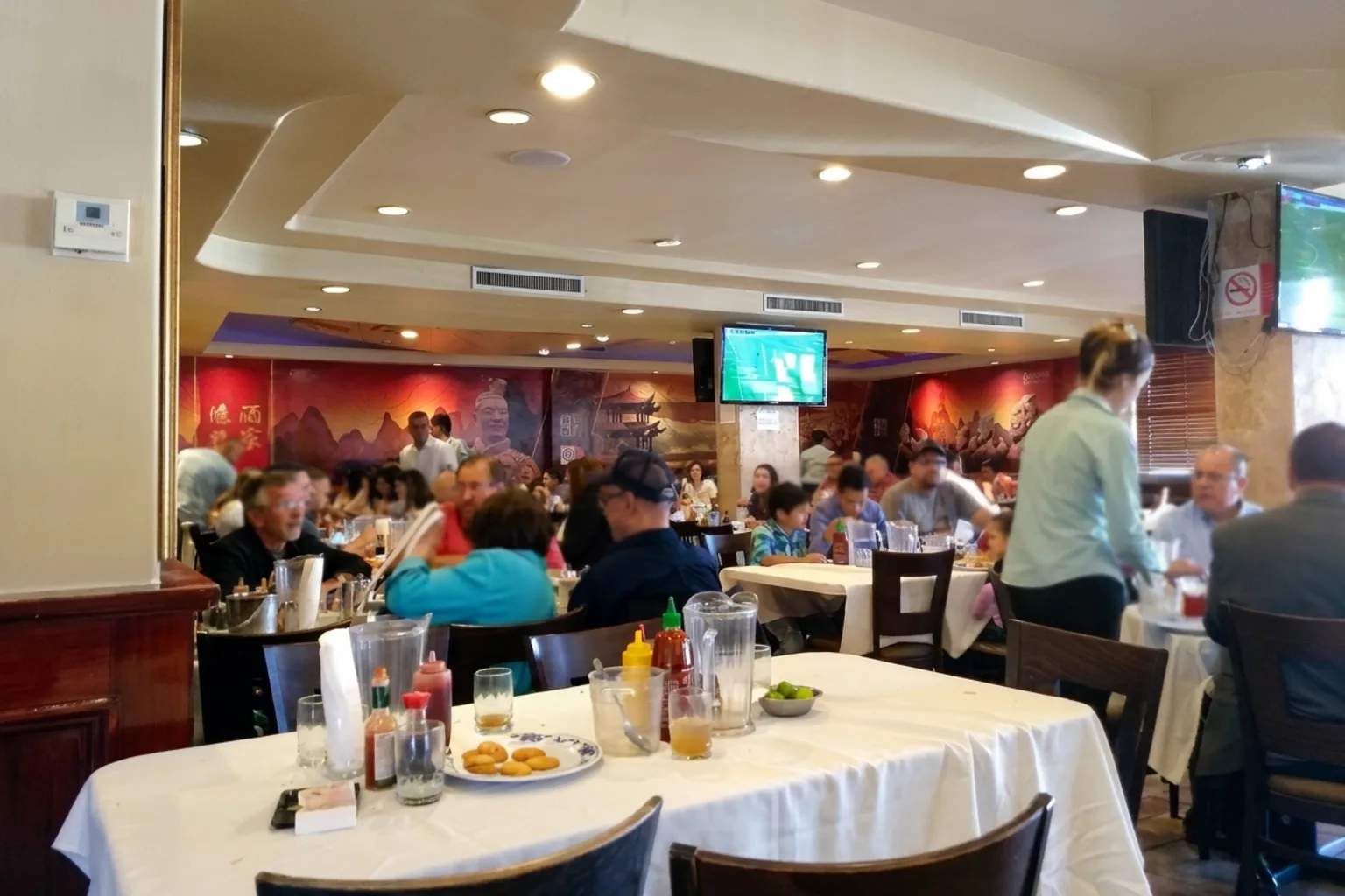 Restaurante China House Mexicali - Salón de mantel blanco con el mural rojo de montañas y guerreros de terracota