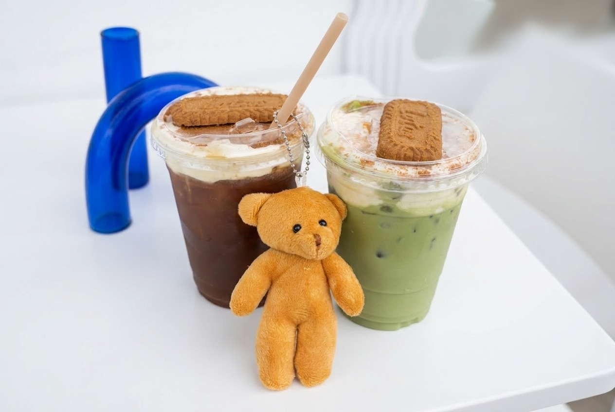 Americano y matcha con cold foam y galleta Lotus junto a un osito de peluche en Kuma Coffee, Mexicali